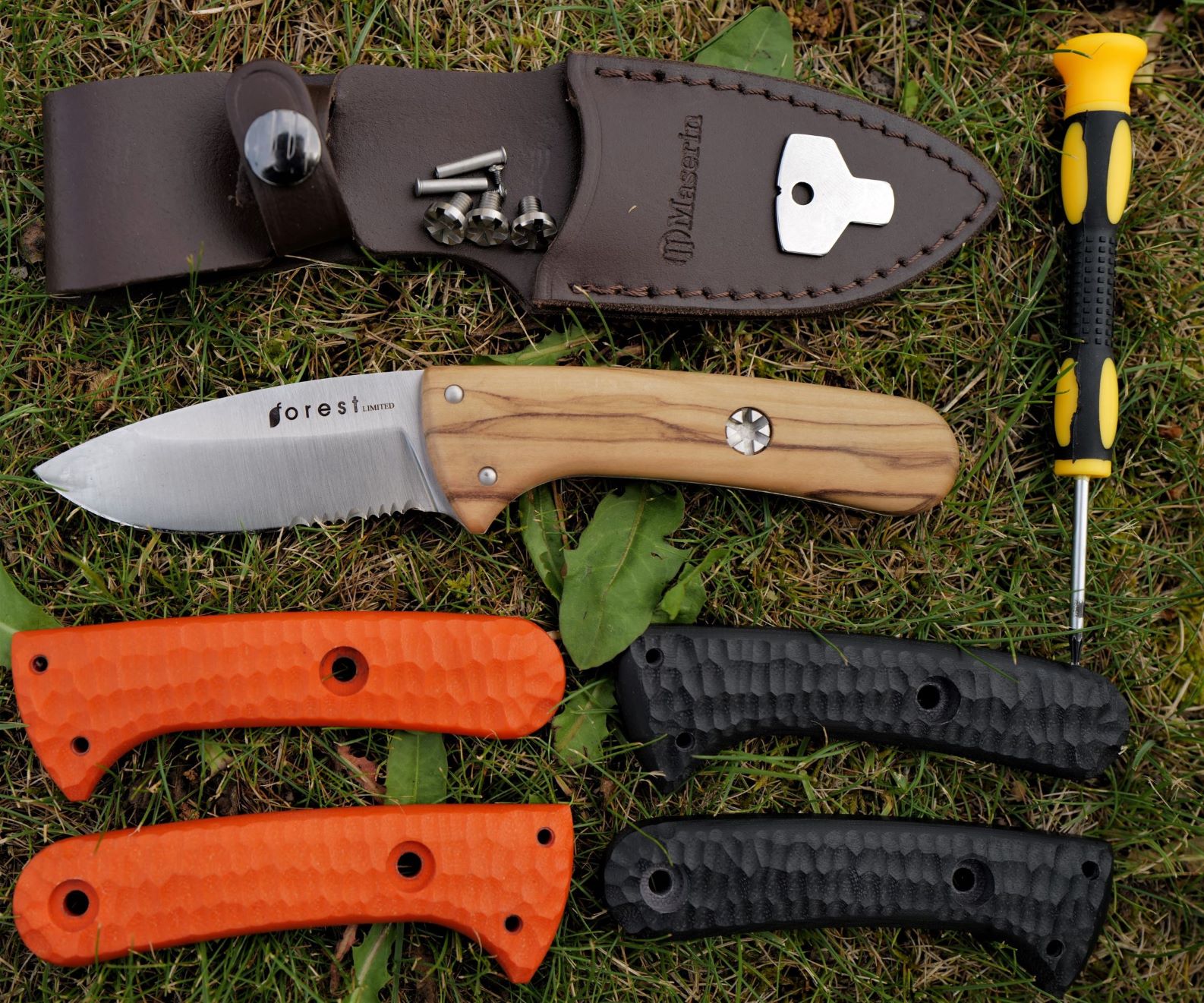 Il contenuto della confezione di Forest Hunting Limited comprende il coltello con il manico in olivo, il fodero in pelle, le guancette di ricambio in resina G10 arancioni e nere, e gli utensili per sostituirle.